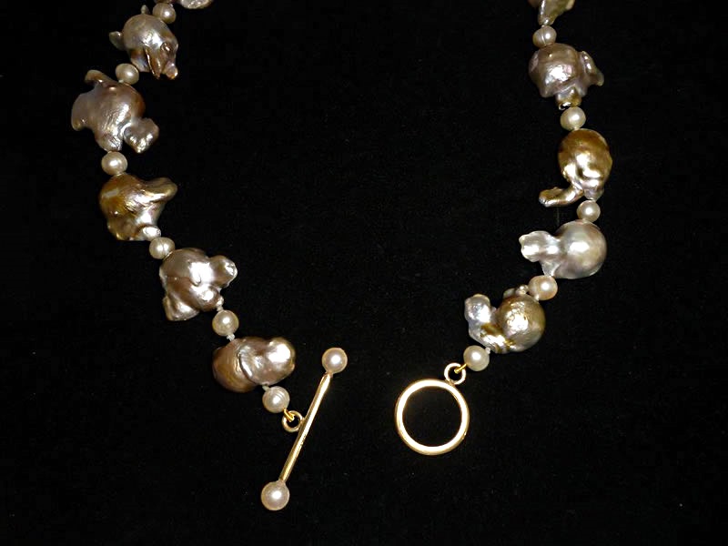 9CT GOLD, T-BAR AND RING FASTENING ON A STRING OF FRESHWATER PEARLS